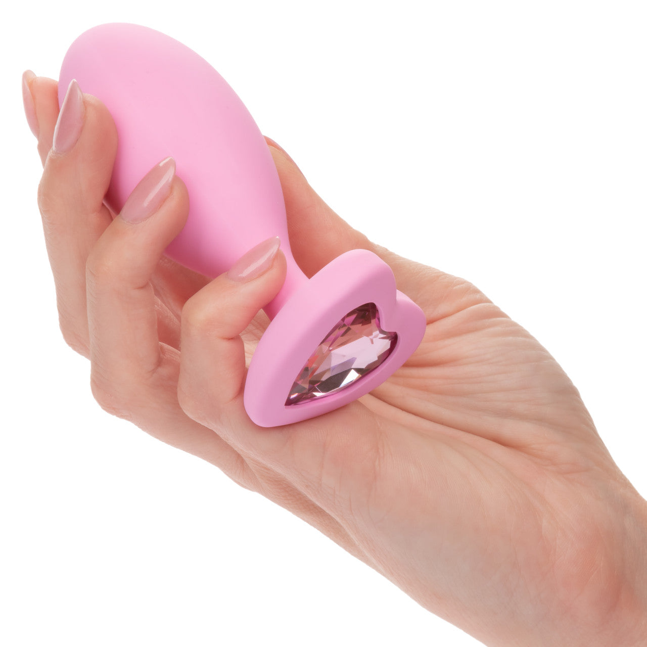 Hand holding pink egg shaped anal plug with a heart shaped gem at base.