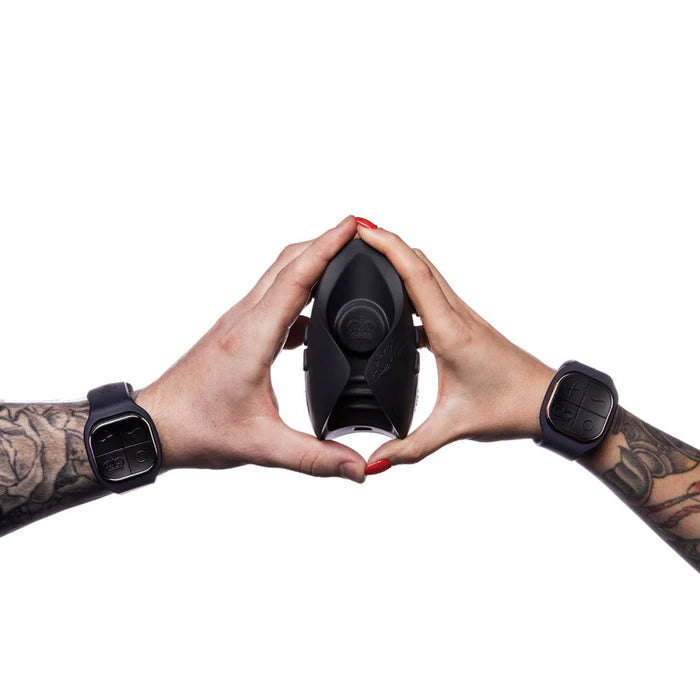 two arms holding the toy, each wearing a wristband remote control, Cylindrical dark gray toy with two wristband remotes, great couples sex toy