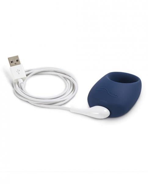 dark blue cock ring with one thick side for the vibrating motor., plugged into white USB charger.